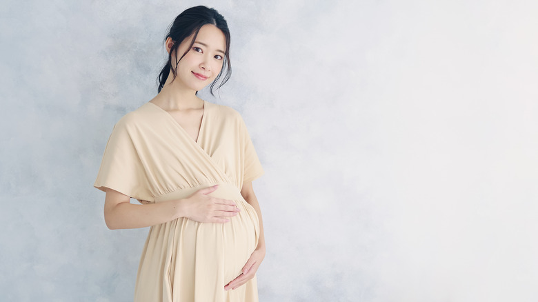 Asian woman holding her pregnant belly