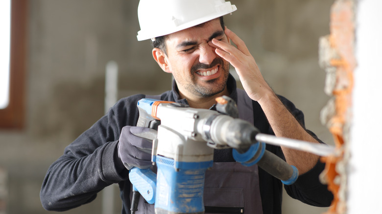 man holding drill who has eye pain