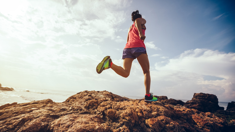 woman running along a rocky trail along the ocean 