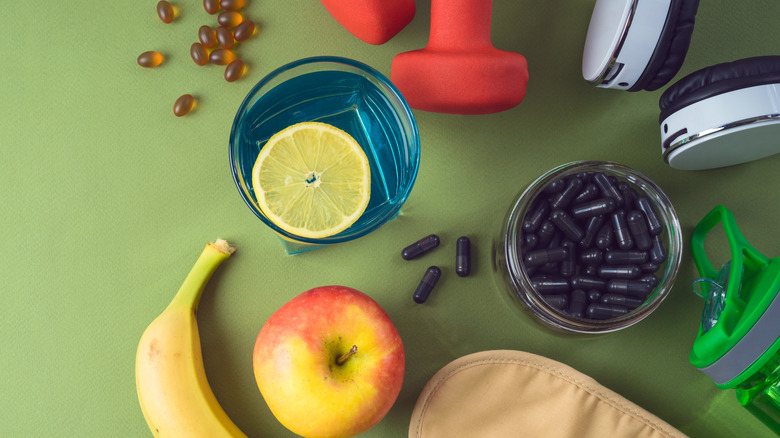 Weights and fruits on green background