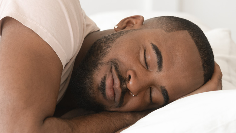 Man with closed eyes sleeping on his side in bed