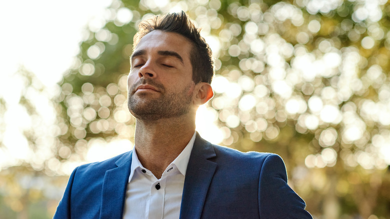 Man wearing suit takes deep breath outside