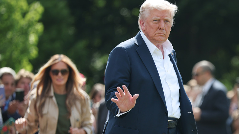 President Donald Trump acknowledging crowd by waving in a suit