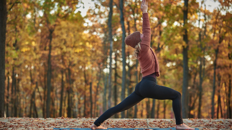 A woman does yoga outside in autumn