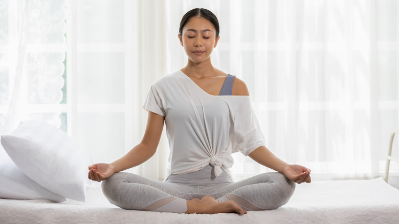 Woman meditating on bed