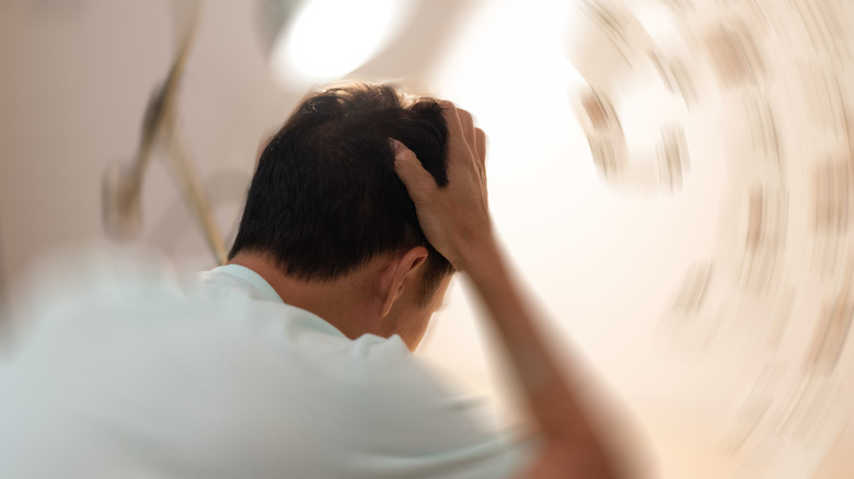 Man with hands on his head suffers from dizziness