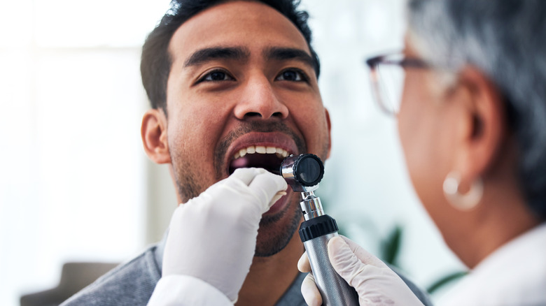 dentist doing oral cancer screening on man