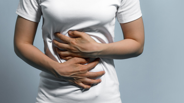 Woman in white tee holding her stomach