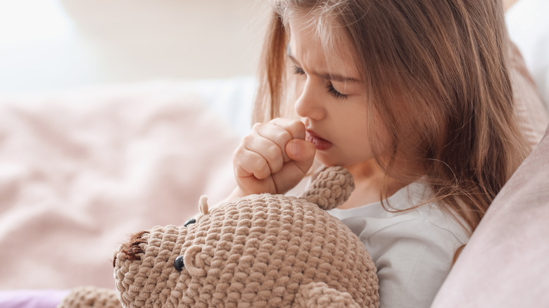 child with teddy bear coughing