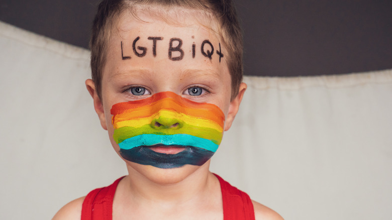 Child with pride flag and letters "LGTBiQ++" on face