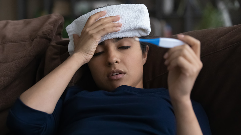 Sick woman holding thermometer 