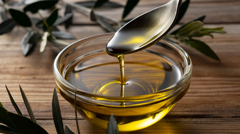 spooning olive oil into bowl