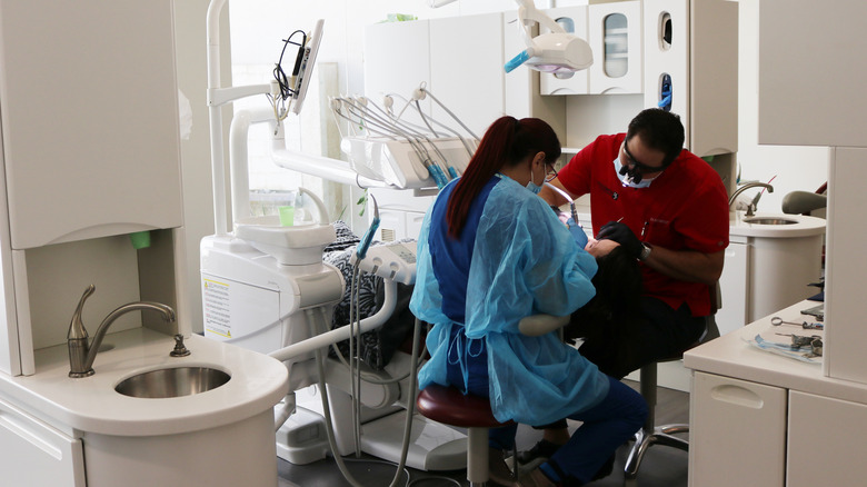 Dentist and assistant work on dental patient