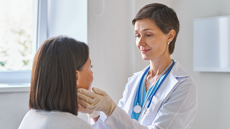 A woman has her thyroid glands check by a doctor