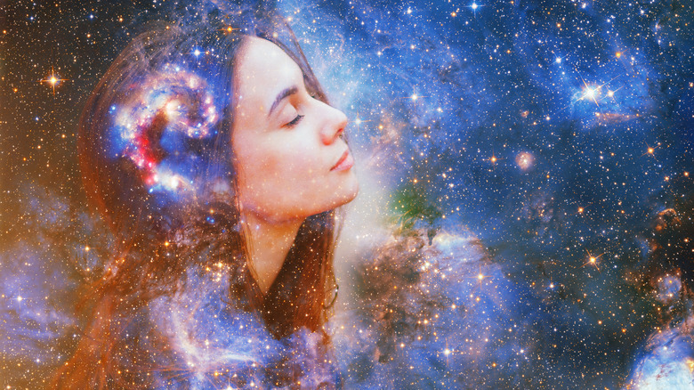 Double exposure image of a woman with her eyes closed overlaid across outer space