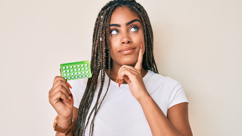 woman thinking about birth control pills