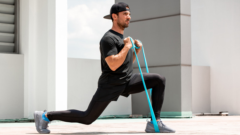 Fit man in a lunge position holding resistance bands