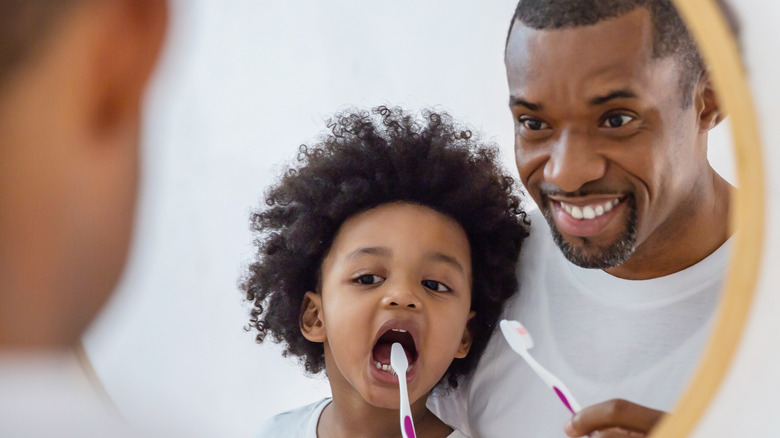 a father and son brushing their teeth together 