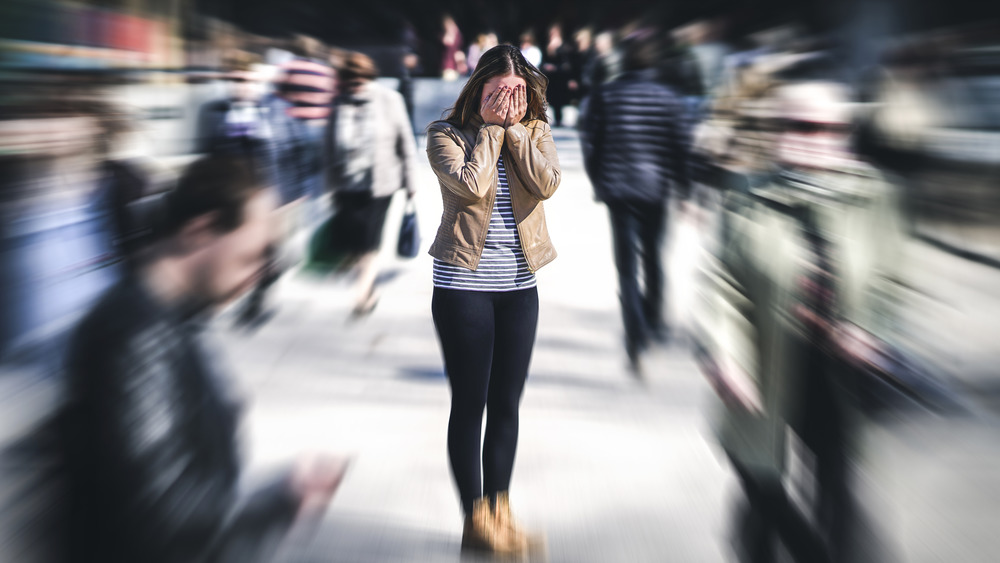 Woman in crowd with hands on face