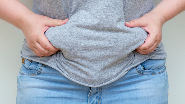 a woman squeezes her abdmonal fat