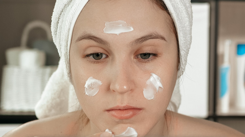 woman applying cream to her face