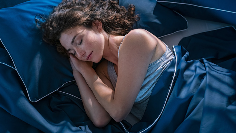 Woman sleeping under blue sheets