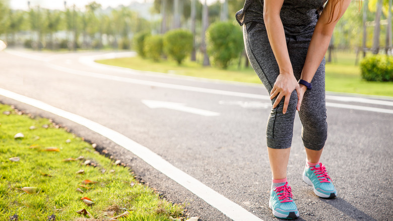 Woman runner holding knee in pain