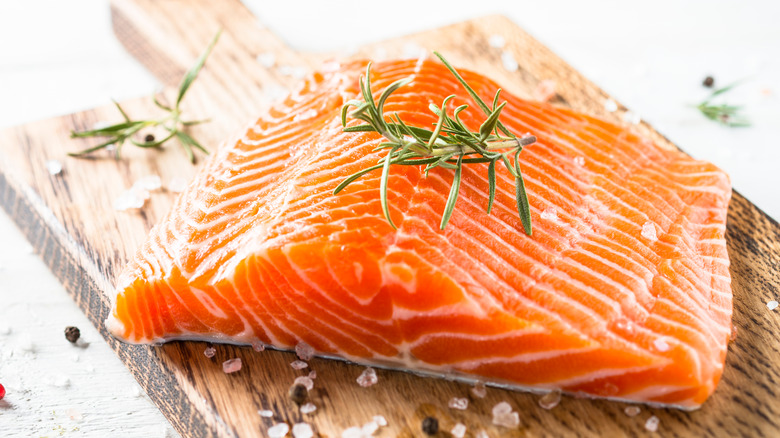 raw salmon fillet on a butcher's block with rosemary 