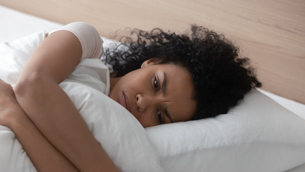 Young woman laying in bed looking depressed