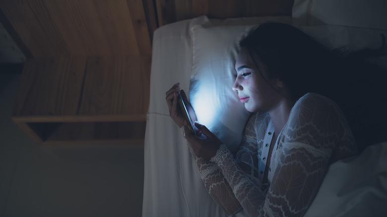 Woman using phone in bed