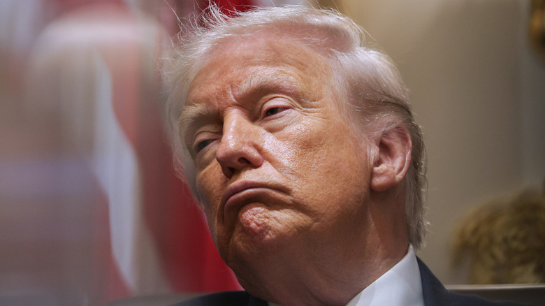Donald Trump with an exaggerated frown, looking off to the left side.