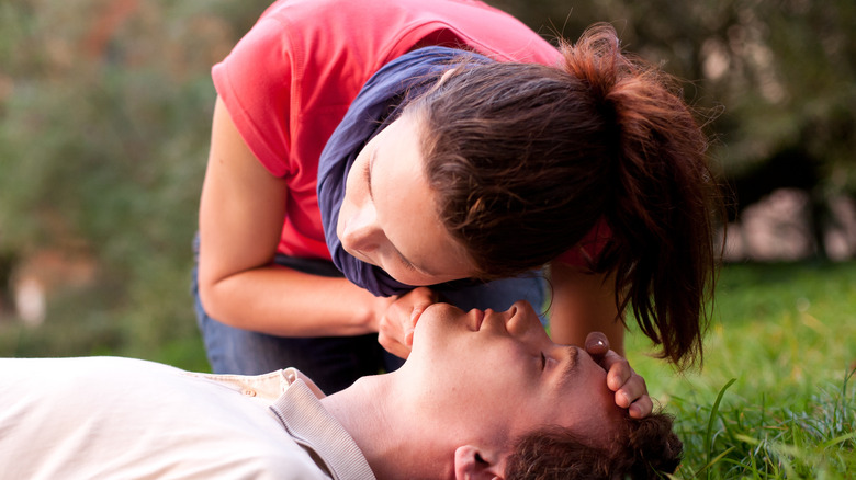 Woman listening for breath sounds from unconscious man