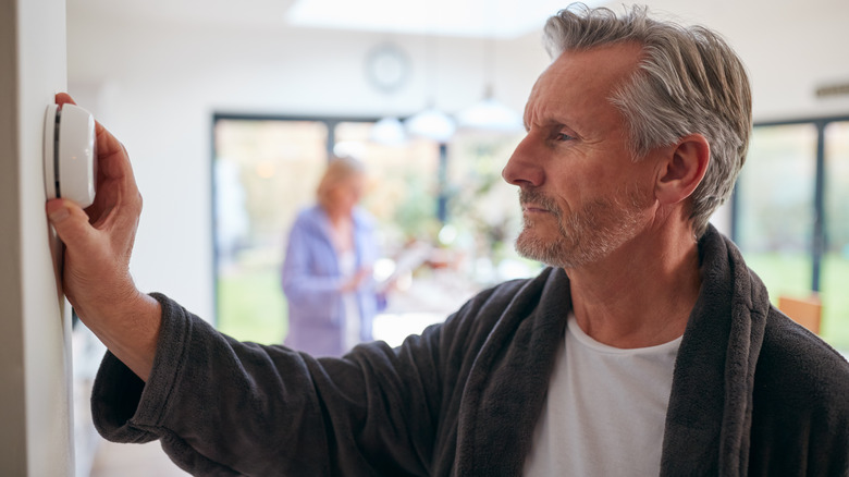 Man in robe setting thermostat