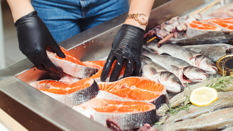 Someone handles raw fish at a shop