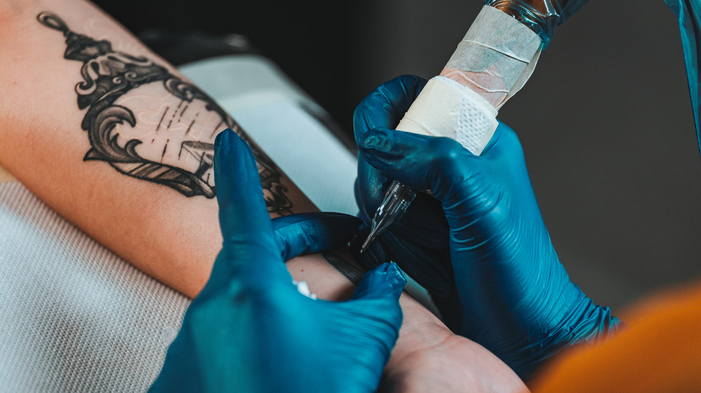 Close up of a tattoo artist applying a black tattoo