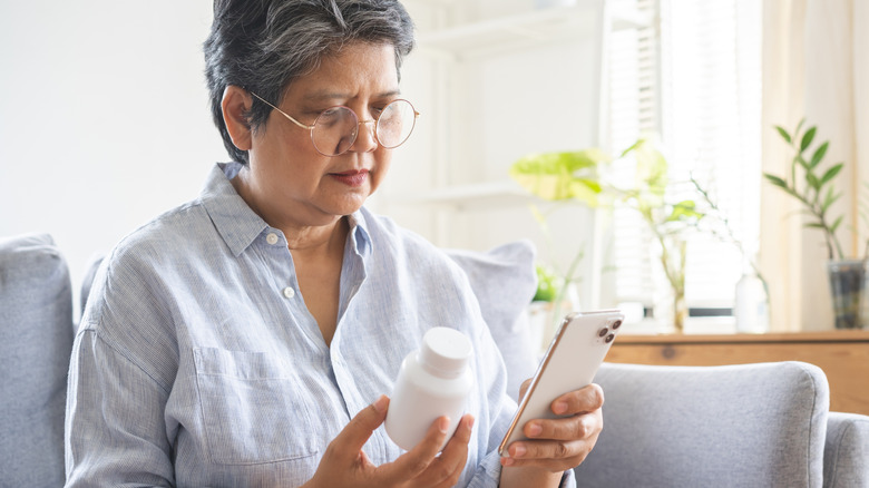 woman looking at pill bottle label