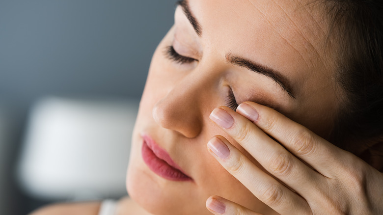 A woman touching her eyelid