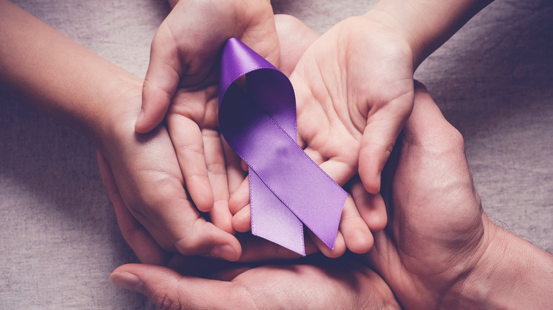 Hands holding purple ribbon