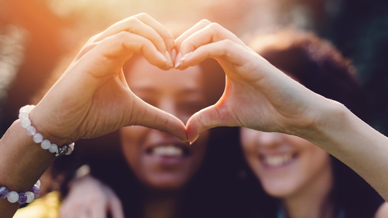 two women joining hands to make heart hands
