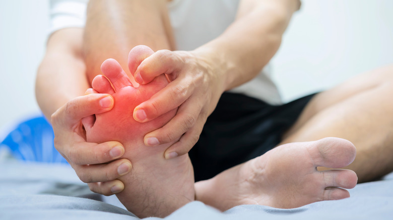 man on bed holding foot