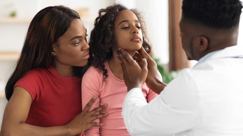 Doctor examining sore throat in child patient