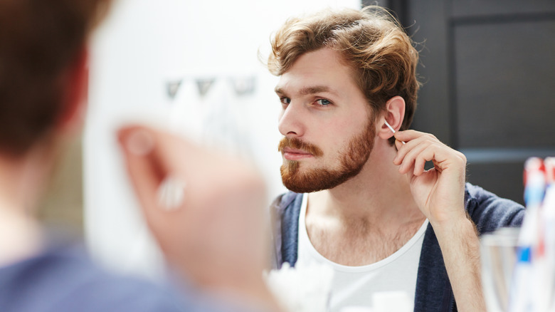 man cleaning ears with q-tip