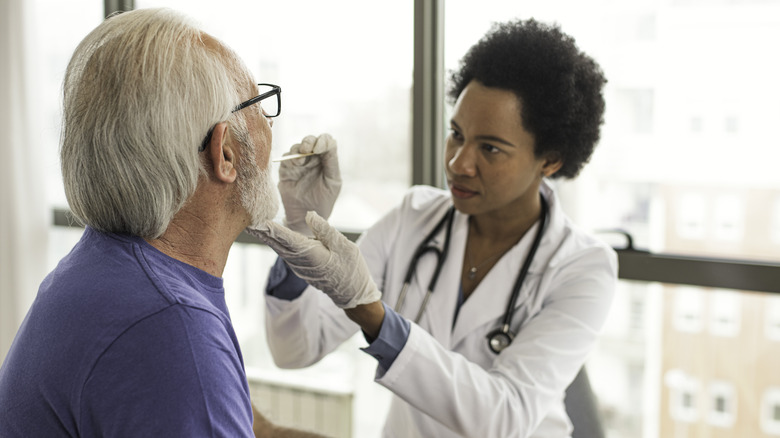 Doctor looking inside patient's mouth