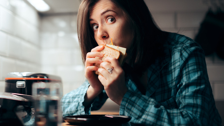 woman eating a sandwich late at night