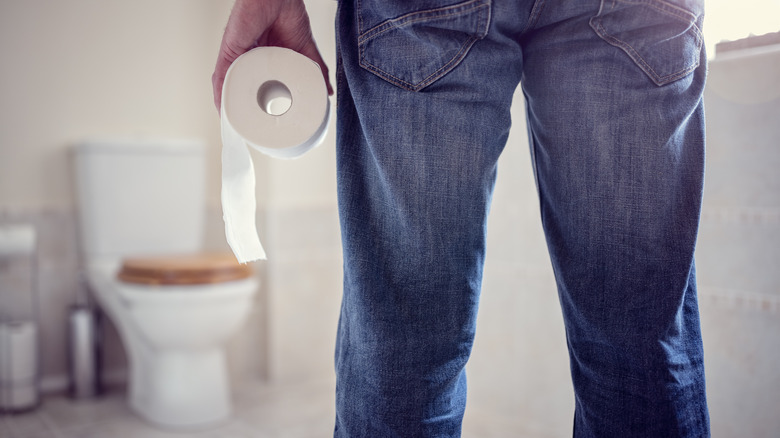 Man in bathroom holding toilet paper