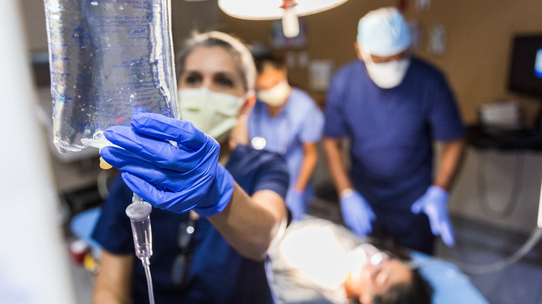 hospital worker checking on an IV bag near patient