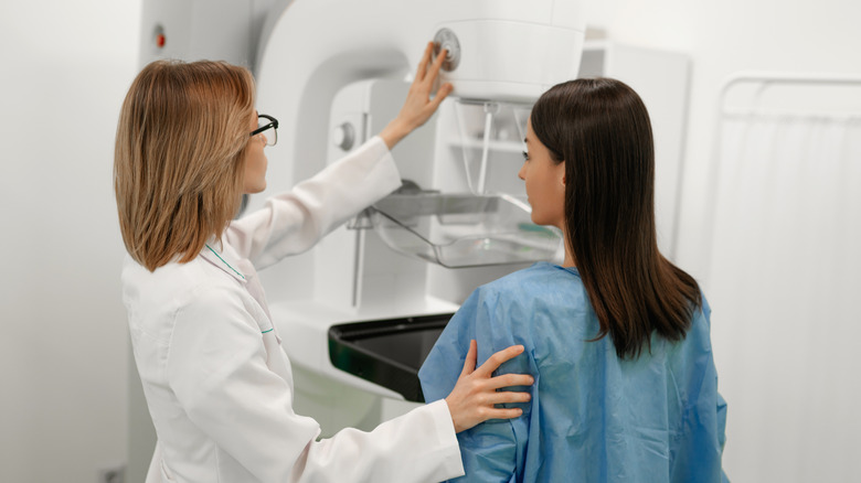 A woman assisted by a technician in getting a mammogram