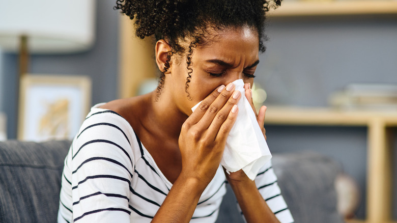 woman sneezing into a tissue