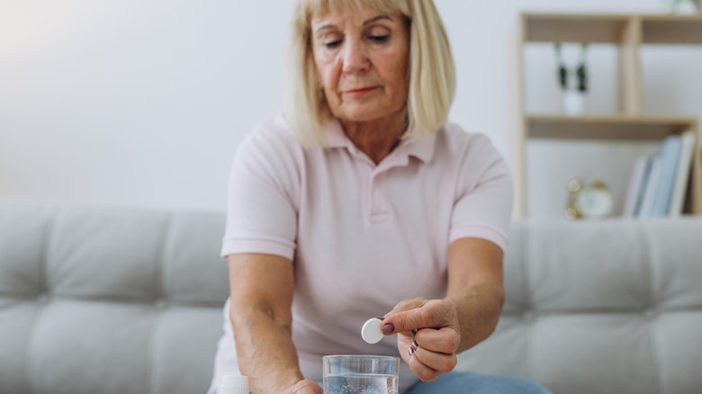 woman putting an antacid tablet into water