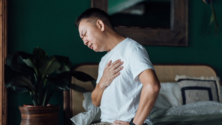 man having heartburn and discomfort on bed